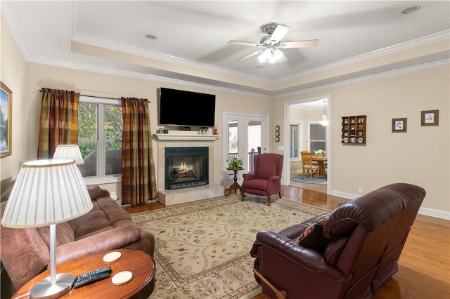 living room featuring hardwood / wood-style flooring, ceiling fan, crown molding, and a tray ceiling