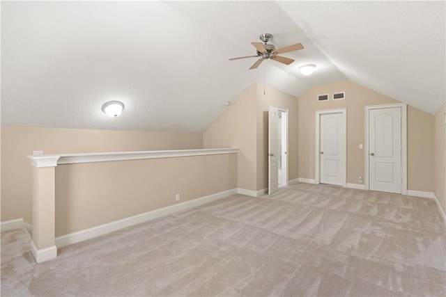 additional living space with light colored carpet, a textured ceiling, and lofted ceiling