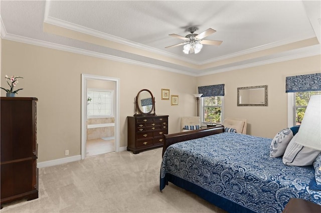 bedroom with a tray ceiling, light carpet, ceiling fan, ensuite bathroom, and crown molding