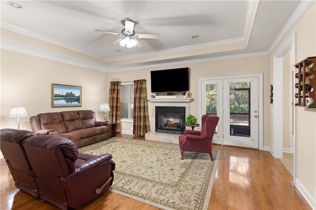 living room with ceiling fan, hardwood / wood-style floors, a tray ceiling, and crown molding