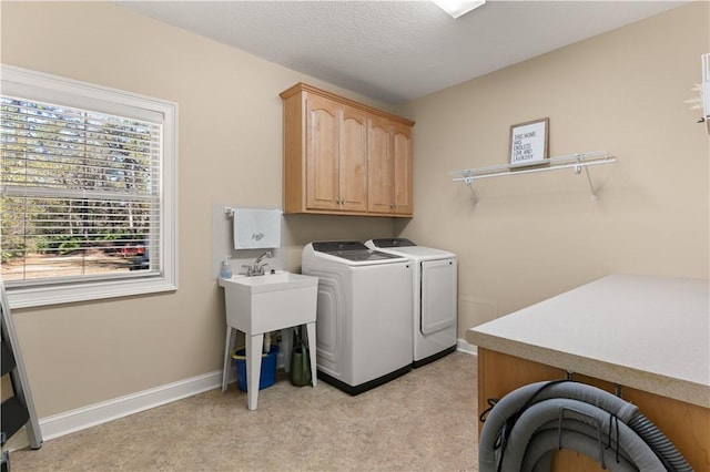 clothes washing area featuring light carpet, washing machine and clothes dryer, a textured ceiling, and cabinets