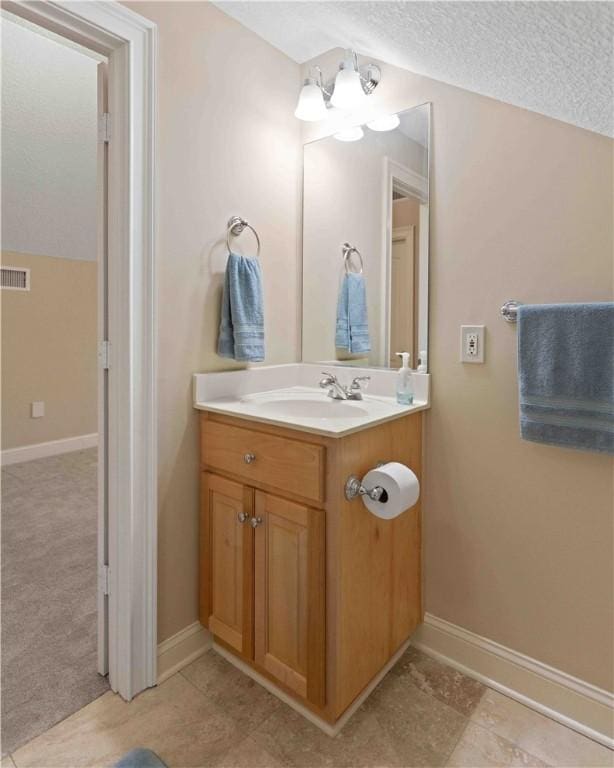 bathroom featuring vanity, vaulted ceiling, a chandelier, and a textured ceiling