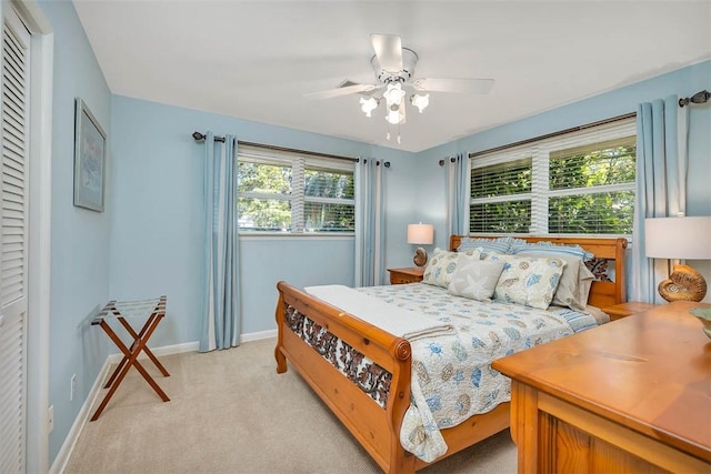 bedroom with light colored carpet, ceiling fan, and baseboards