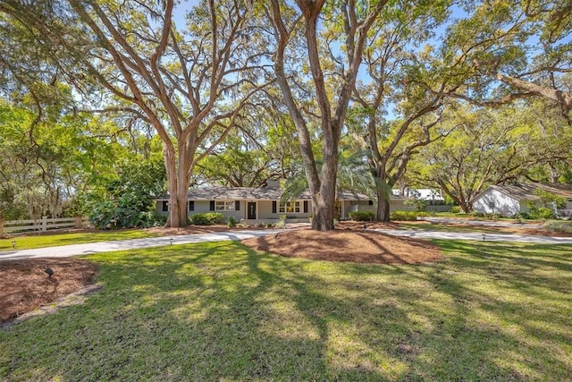 view of front of home featuring concrete driveway, a front lawn, and fence
