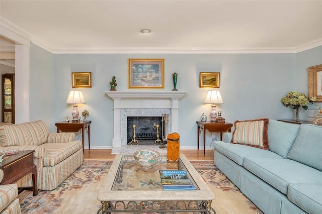 living area with a fireplace, light wood-style flooring, baseboards, and ornamental molding