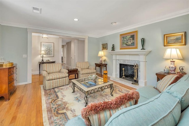 living room featuring light wood-type flooring, a premium fireplace, baseboards, and crown molding