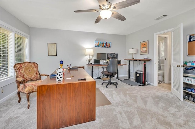 office space featuring carpet floors, visible vents, a ceiling fan, and baseboards
