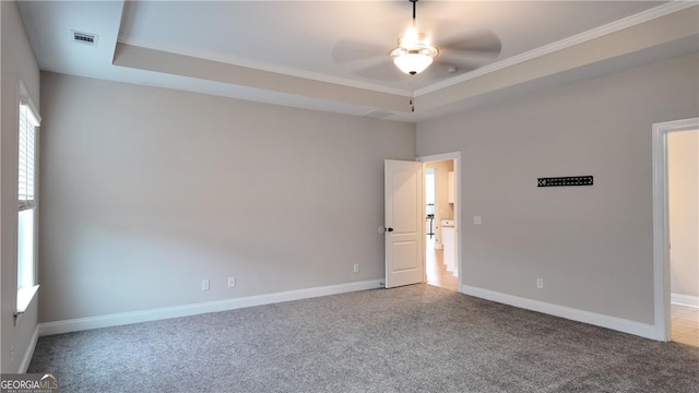 carpeted spare room with crown molding, visible vents, ceiling fan, and baseboards