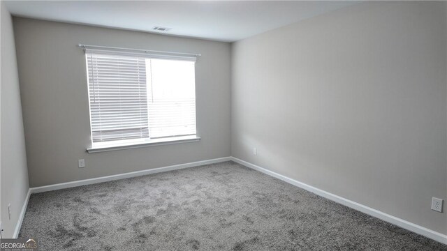 unfurnished room with carpet flooring, visible vents, and baseboards