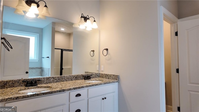 full bath with double vanity, a sink, and a shower with door
