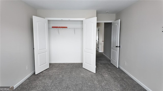 unfurnished bedroom featuring dark carpet, a closet, and baseboards
