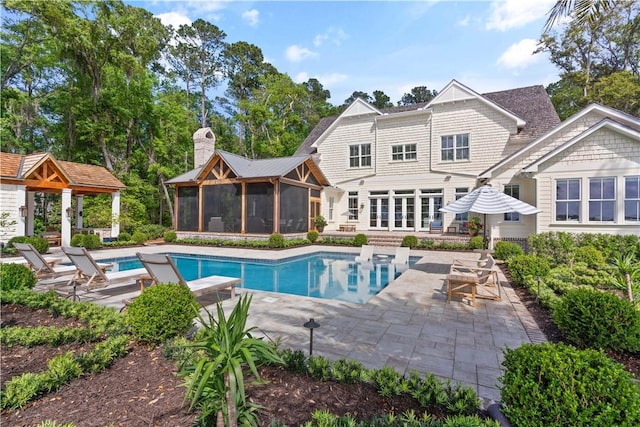 329 Saint Annies Ln, Saint Simons Island, GA 31522 - back of house featuring a sunroom, a chimney, a patio area, and an outdoor pool