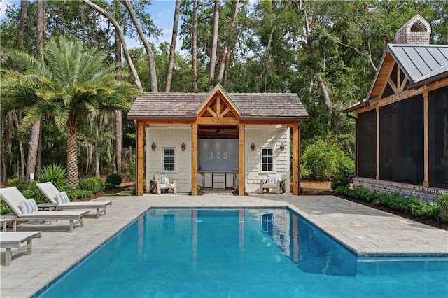 329 Saint Annies Ln, Saint Simons Island, GA 31522 - swimming pool with a storage structure, an outbuilding, a patio area, a sunroom, and view of scattered trees