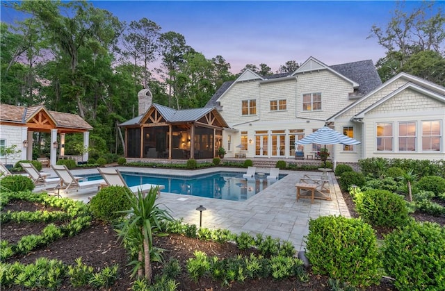 329 Saint Annies Ln, Saint Simons Island, GA 31522 - back of property featuring a patio, a sunroom, a chimney, and an outdoor pool