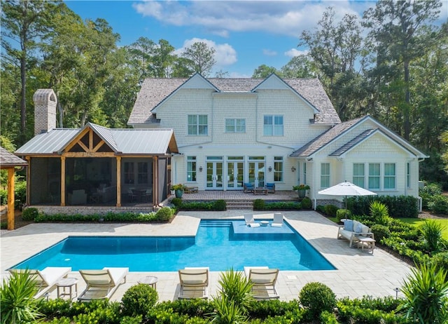 329 Saint Annies Ln, Saint Simons Island, GA 31522 - rear view of house featuring a patio, a sunroom, an outdoor pool, french doors, and a chimney