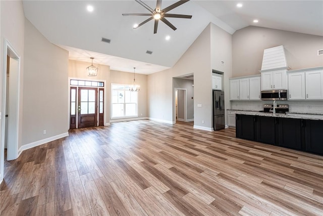 119 Silver Bluff Dr, Brunswick, GA 31523 - kitchen with stainless steel microwave, refrigerator with ice dispenser, open floor plan, high vaulted ceiling, and a chandelier