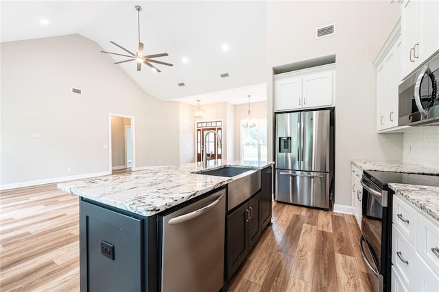 119 Silver Bluff Dr, Brunswick, GA 31523 - kitchen featuring appliances with stainless steel finishes, high vaulted ceiling, light wood-type flooring, white cabinetry, and an island with sink