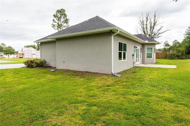 119 Silver Bluff Dr, Brunswick, GA 31523 - view of side of home with a yard, stucco siding, roof with shingles, and a patio
