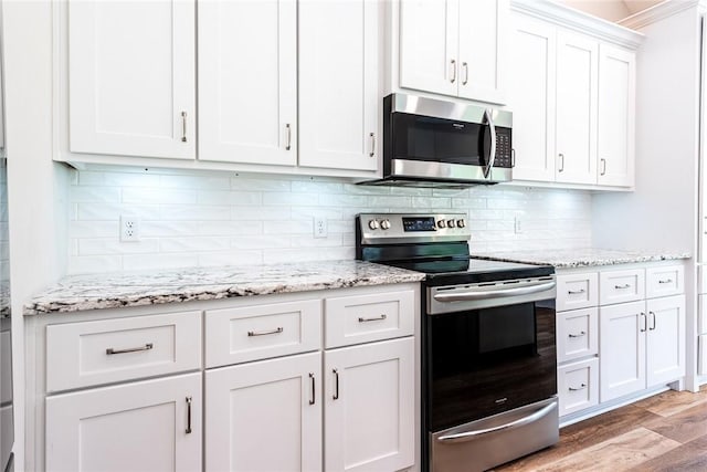 119 Silver Bluff Dr, Brunswick, GA 31523 - kitchen with stainless steel appliances, light wood finished floors, white cabinetry, backsplash, and light stone counters