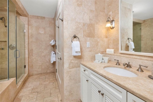 bathroom with vanity, an enclosed shower, and tile walls