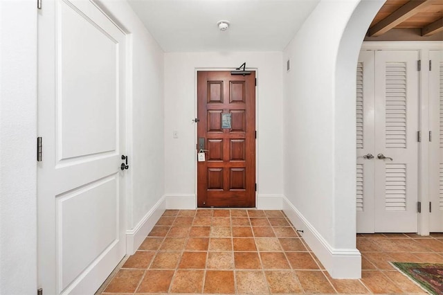 doorway to outside featuring beam ceiling