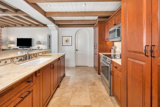 kitchen with beamed ceiling, appliances with stainless steel finishes, and sink