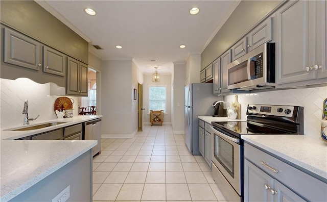 kitchen with gray cabinetry, sink, crown molding, light tile patterned flooring, and appliances with stainless steel finishes