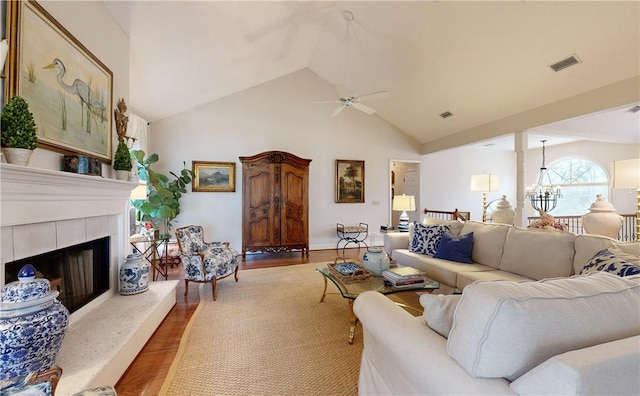 living room featuring ceiling fan with notable chandelier, light hardwood / wood-style flooring, and vaulted ceiling