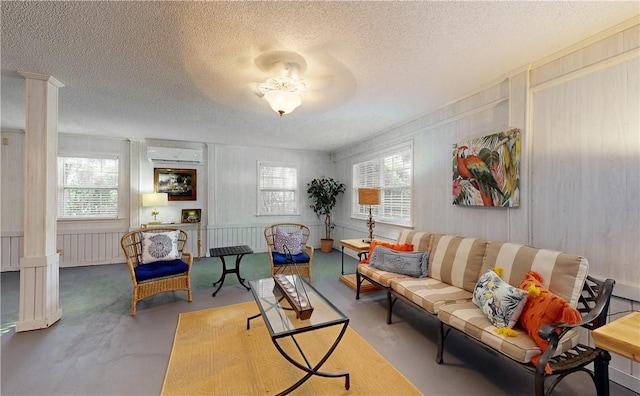 living room featuring a wall mounted air conditioner, ceiling fan, concrete flooring, and a textured ceiling