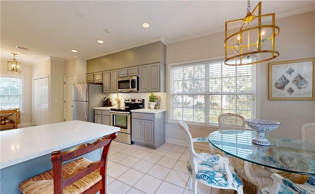 kitchen with a wealth of natural light, gray cabinets, appliances with stainless steel finishes, and a chandelier