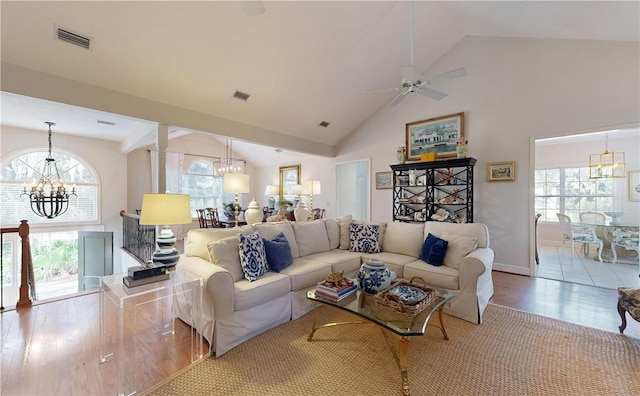 living room featuring ceiling fan with notable chandelier, light wood-type flooring, and high vaulted ceiling