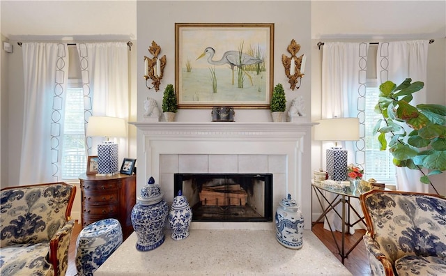 sitting room with a tile fireplace, a wealth of natural light, and hardwood / wood-style flooring