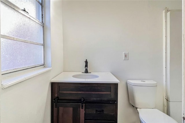 bathroom featuring vanity, toilet, and a healthy amount of sunlight