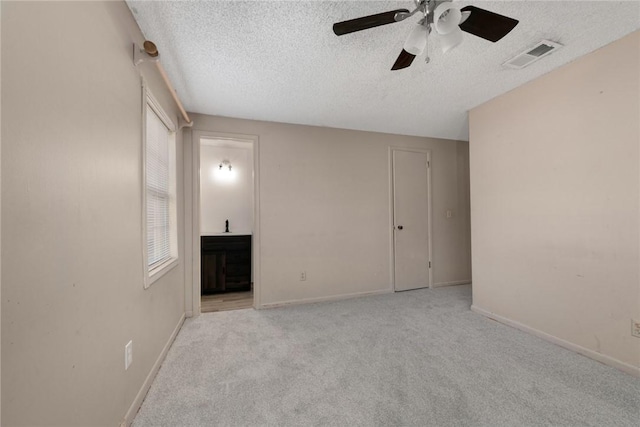 unfurnished room featuring ceiling fan, light colored carpet, and a textured ceiling