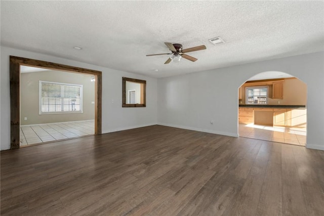 unfurnished living room with ceiling fan, dark hardwood / wood-style flooring, and a textured ceiling