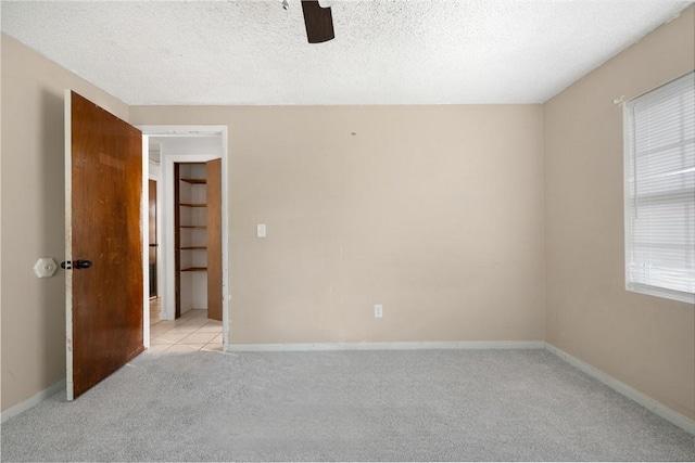 spare room with ceiling fan, light colored carpet, and a textured ceiling