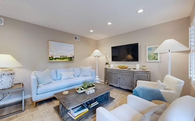 living area with baseboards, light wood-type flooring, visible vents, and recessed lighting