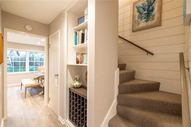 staircase featuring wood-type flooring and wooden walls