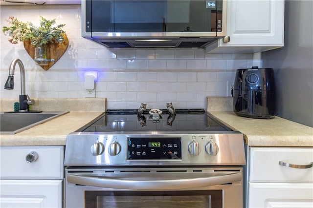 kitchen featuring decorative backsplash, sink, white cabinetry, and stainless steel appliances