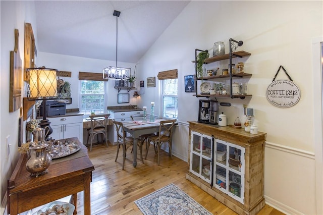 dining room with light hardwood / wood-style floors, a chandelier, and lofted ceiling