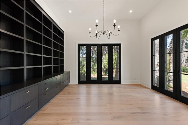 entryway featuring french doors, an inviting chandelier, and light hardwood / wood-style flooring