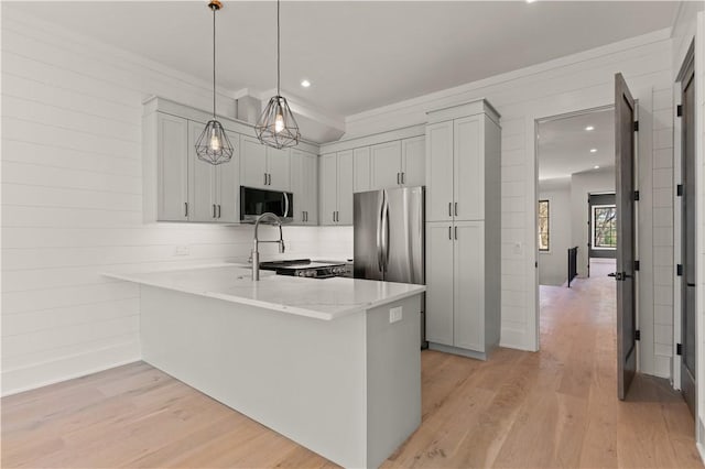 kitchen featuring kitchen peninsula, appliances with stainless steel finishes, light wood-type flooring, and pendant lighting