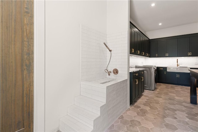 kitchen featuring washer and clothes dryer, decorative backsplash, and sink