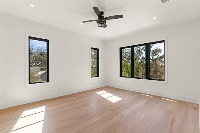 empty room featuring light hardwood / wood-style flooring, ceiling fan, and a healthy amount of sunlight