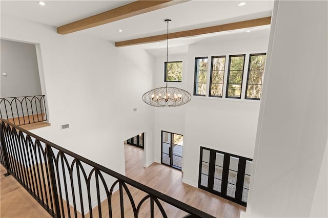 staircase featuring beam ceiling, a chandelier, and hardwood / wood-style flooring