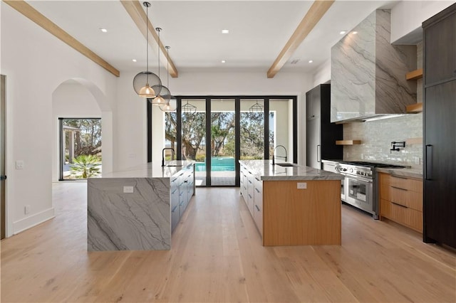 kitchen with pendant lighting, double oven range, a spacious island, light stone countertops, and tasteful backsplash