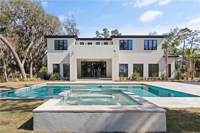 rear view of house featuring a swimming pool with hot tub and a balcony