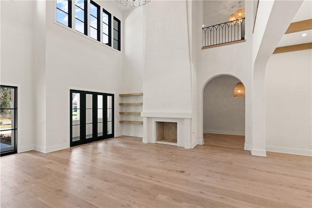 unfurnished living room with a high ceiling and light wood-type flooring