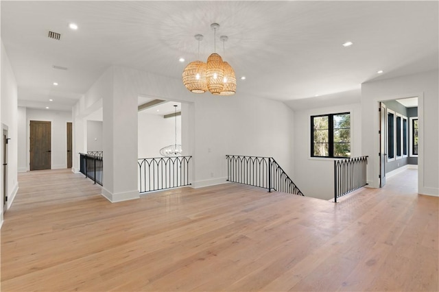 unfurnished room with a chandelier and light hardwood / wood-style floors