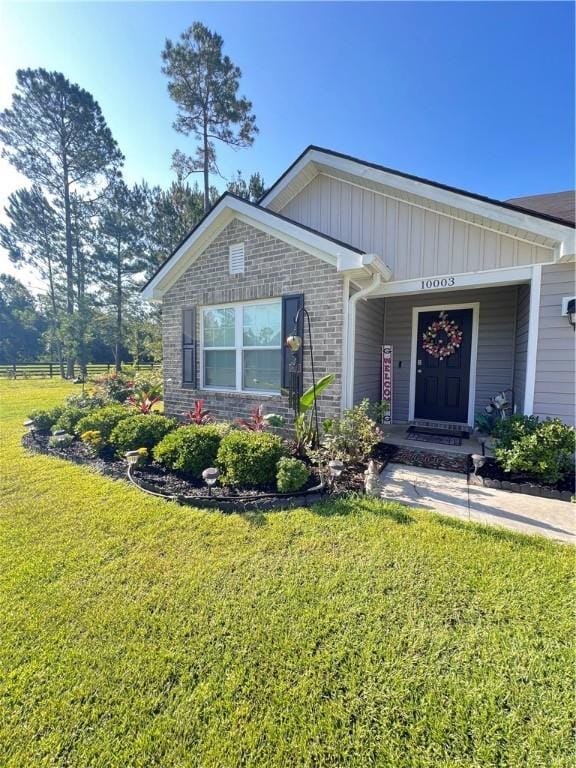 10003 Woodland Cv, Brunswick, GA 31525 - view of front facade featuring a front yard, board and batten siding, and brick siding